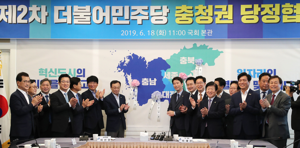 더불어민주당 이해찬 대표(왼쪽에서 일곱번째) 등 참석자들이 18일 오전 국회에서 열린 제2차 더불어민주당 충청권 당정협의회에서 충남, 대전, 세종, 충북 등의 지도에 꽃달기 퍼포먼스를 한 뒤 박수치고 있다./연합뉴스