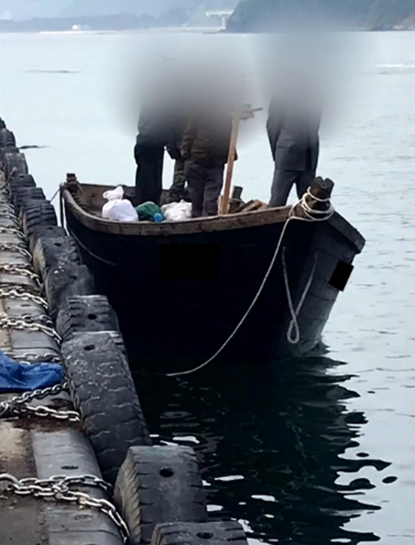 지난 15일 북한에서 온 4명이 탑승한 어선이 삼척항 방파제에 정박해 있는 모습. 이 가운데 일부가 전투복 등을 입고 있는 모습이 보인다. /KBS