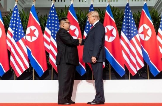 도널드 트럼프 미국 대통령과 김정은 북한 국무위원장이 2018년 6월 12일 싱가포르 카펠라 호텔에서 정상회담을 위해 만나 악수하고 있다. 뒤에 미국 성조기와 북한 인공기가 나란히 내걸렸다. /댄 스커비노 백악관 소셜미디어 국장 트위터