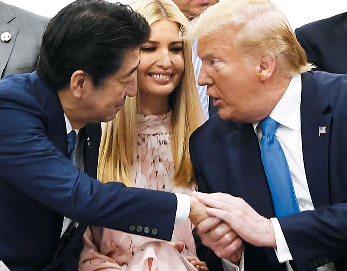 지난달 29일 일본 오사카에서 열린 주요 20국(G20) 정상회담의 특별 세션에서 도널드 트럼프(오른쪽) 미 대통령과 아베 신조(왼쪽) 일본 총리가 이방카 트럼프(가운데)를 사이에 두고 손을 붙잡고 이야기하고 있다.