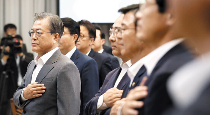 문재인 대통령이 9일 청와대에서 열린 ‘공정경제 성과 보고 회의’에서 참석자들과 함께 국기에 경례하고 있다.