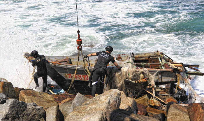 해양경찰특공대원들이 12일 강원도 고성군 해안에서 이날 오전 10시 37분쯤 발견된 북한 소형 목선(木船)을 인양하고 있다.