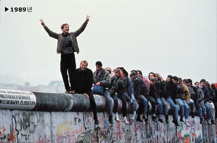 1989년 11월 9일 서베를린의 젊은이들이 베를린 포츠담 광장을 동서로 가르는 장벽이 무너지자 그 위에 올라가 기뻐하고 있다