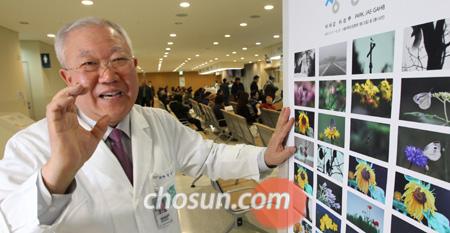 박재갑 교수가 21일 자신의 작품이 걸릴 서울대학교 암병원 2층 복도에서 전시회 포스터에 대해 설명하고 있다. 포스터에 인쇄된 이미지 28점 중 앞쪽 14점은 사진이고, 나머지는 그림이다. /이명원 기자
