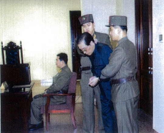 북한이 이례적으로 공개한 포승줄에 양 손이 묶인 장성택이 국가안전보위부원들에게 붙들린 채 법정에 선 모습. 2013년 12월 12일 열린 특별군사재판 후 장성택은 국가전복음모행위로 사형을 당했다.