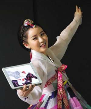 조각보로 만든 한복을 입은 김현정 작가. 태블릿PC 안 그림은 한복 차림으로 승마하는 여인을 그린 작품이다.