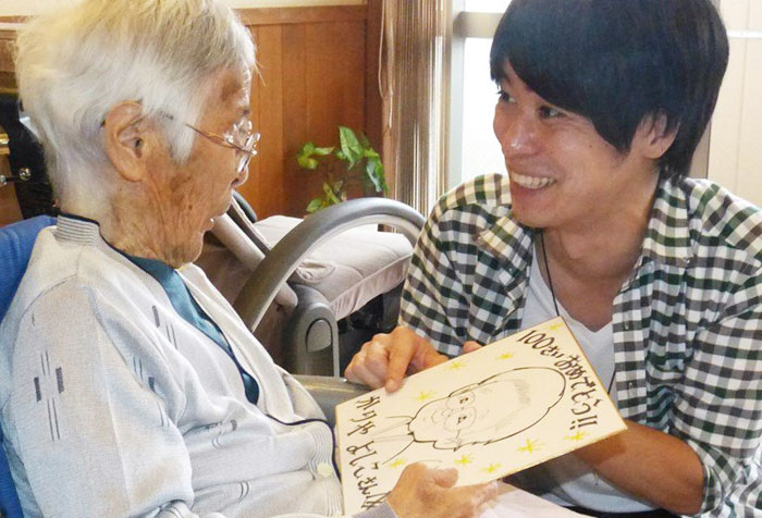 일본 미에현에 있는 요양원에 입소한 노인(왼쪽)에게 한 청년 자원봉사자가 자신이 그린 초상화를 선물하고 있다.