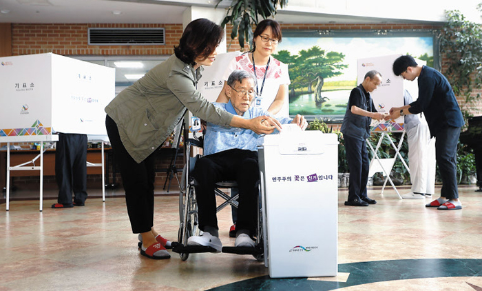 지난 5일 경기 수원 권선구 중앙양로원에서 휠체어를 탄 노인이 선관위 직원과 양로원 관계자의 도움을 받아 기관·시설 거소투표를 하고 있다. 거소투표는 선거 당일 유권자가 투표소로 갈 수 없는 경우 거처하는 곳에서 투표할 수 있도록 하는 제도다.
