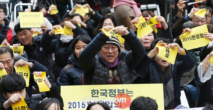 정부가 위안부 피해 할머니 지원을 위해 만든 ‘화해·치유재단’을 해산하겠다고 발표한 21일 서울 종로구 옛 일본 대사관 앞에서 정기 수요 시위 참가자들이 ‘2015 한일합의’라고 쓰인 종이를 찢고 있다.