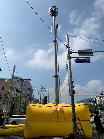 12일 오전 대구 남구 영대병원네거리 교통관제 폐쇄회로(CC)TV 타워에 한 남성이 올라가 있는 가운데, 경찰이 만일의 사태를 대비해 에어매트를 설치해놨다. /대구 남부경찰서 제공
