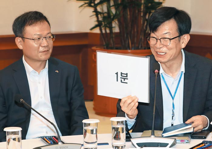 김상조(오른쪽) 청와대 정책실장이 10일 청와대 간담회에서 기업인들에게 발언 시간을 지켜 달라며 '1분' 남았다는 팻말을 들고 있다.