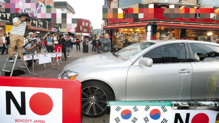 23일 오후 인천 남동구 구월동에서 한 상인(가운데)이 자신의 은색 렉서스 차량을 쇠파이프로 부수고 있다. 상인은 “일본에 강한 불매운동 의지를 보여줄 필요가 있다고 생각했다”고 밝혔다.