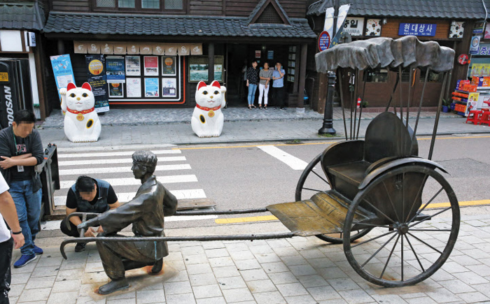 30일 오후 인천 중구 관계자들이 구 청사 앞 개항장거리에 설치된 인력거 끄는 남성 동상의 철거 준비 작업을 하고 있다. 길 건너편으로 일본 행운의 고양이 조형물이 보인다. 동상과 조형물은 철거 뒤 구청 창고로 옮겨졌다.
