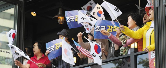 이날 집회에 참가하기 위해 광화문·시청 일대 카페를 찾은 시민들이 창문 너머로 태극기와 '조국 아웃' 손팻말을 흔들고 있다.