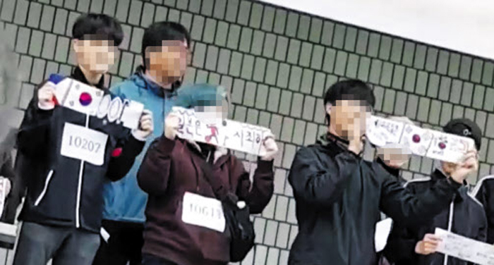 지난 17일 서울 A고의 ‘달리기 걷기 어울림 한마당’ 행사에서 단상에 오른 학생들이 ‘일본은 사죄하라’는 구호를 적은 종이와 태극기를 펼쳐보이고 있다. A고 일부 교사는 행사 1주일 전부터 학생들에게 이 같은 그림을 만들도록 했다.