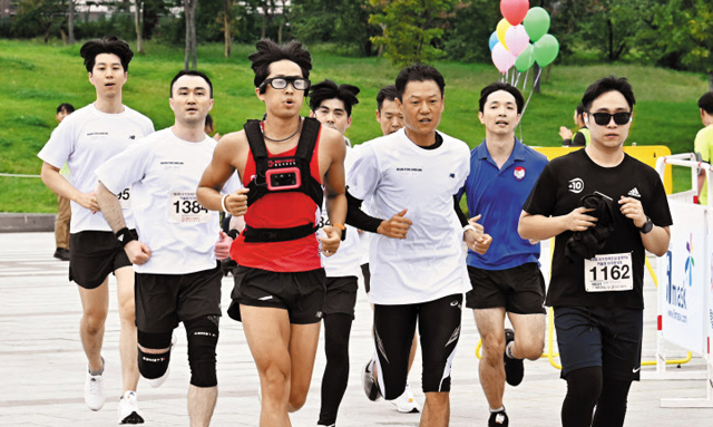 시각장애인 마라토너 한동호씨가 시각장애인용 웨어러블 스마트기기 ‘웰컴드림글래스’를 착용하고 일반인들과 함께 마라톤 코스를 뛰고 있다.