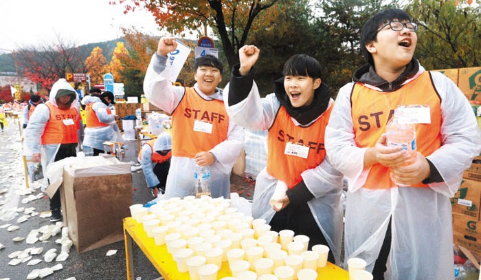 춘천마라톤 자원봉사자는 물과 음료를 건네는 것은 물론 힘까지 북돋아주는 훌륭한 완주 도우미다. 지난해 대회에서 급수대를 맡은 학생들이 러너들을 응원하는 모습.