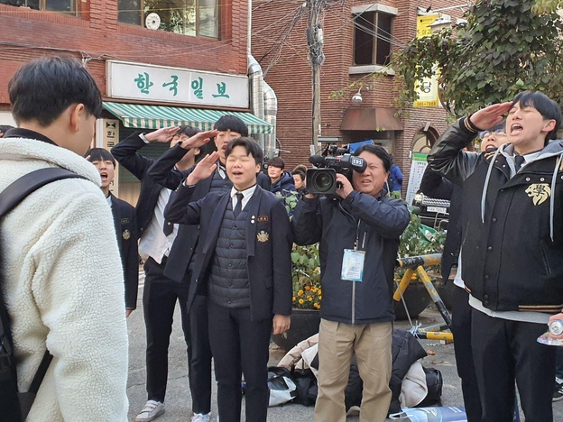 14일 서울 서초고 앞에서 중동고 응원단 학생들이 수능시험을 보는 선배 수험생에게 거수 경례를 하고 있다./ 정민하 기자