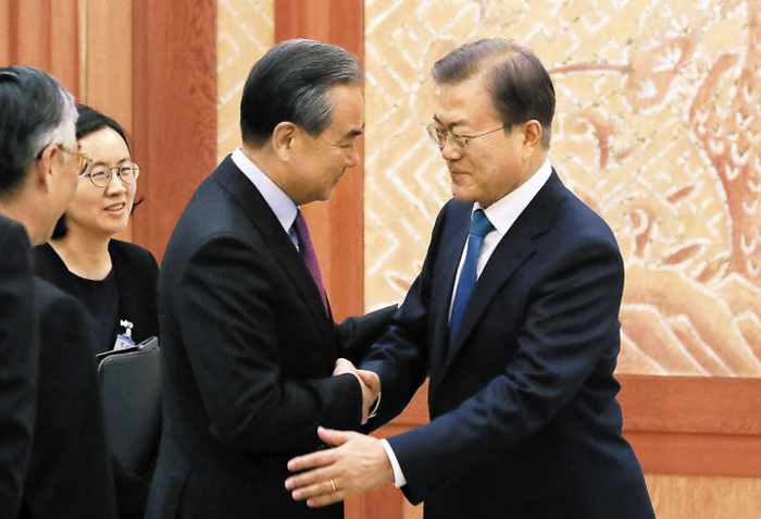 文대통령 만나 미국 비판한 왕이 - 문재인 대통령이 5일 청와대 본관 접견실에서 왕이(王毅) 중국 외교 담당 국무위원 겸 외교부장과 악수하고 있다. 문 대통령은 “시진핑 국가주석의 국빈 방문이 내년 상반기 조기에 이루어지길 기대한다”고 했다. 왕 부장은 “국제 정세는 일방주의와 강권 정치의 위협을 받고 있다”고 했다. 트럼프 미 행정부의 자국 우선주의 정책을 비판한 것으로 풀이됐다.