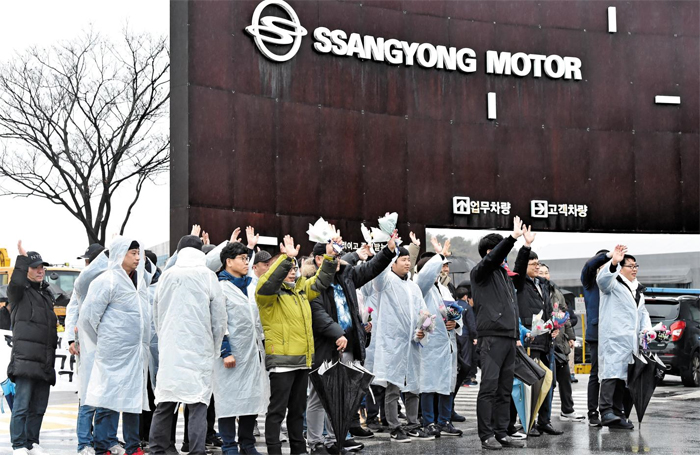 쌍용차 해고 근로자 34명이 7일 경기도 평택 쌍용자동차 공장 안에 들어가 손을 흔들고 있다. 해고된 지 10년 7개월 만에 첫 출근 한 이들은 이날 기자회견을 열고 “회사 측이 복직 후 부서 배치를 해 주겠다는 약속을 깼다”고 반발했다. 지난달 30일 특별 사면된 한상균(왼쪽에서 넷째) 전 민노총 위원장도 이날 34명 중 한 명으로 출근했다.