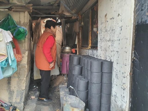 지난 8일 오후 서울 노원구 중계본동 백사마을에 사는 곽오단(88) 할머니가 연탄난로를 들여다보고 있다. 난로 옆에는 연탄은행에서 받은 연탄 70여 개가 쌓여 있다. /정민하 기자