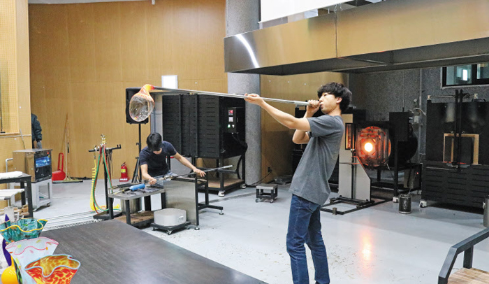 지난 2일 강원 삼척시 도계유리나라 공예실에서 유리공예 작가가 대롱 끝에 숨을 불어넣어 액화 유리를 유리 화병으로 만드는 과정을 시연하고 있다.