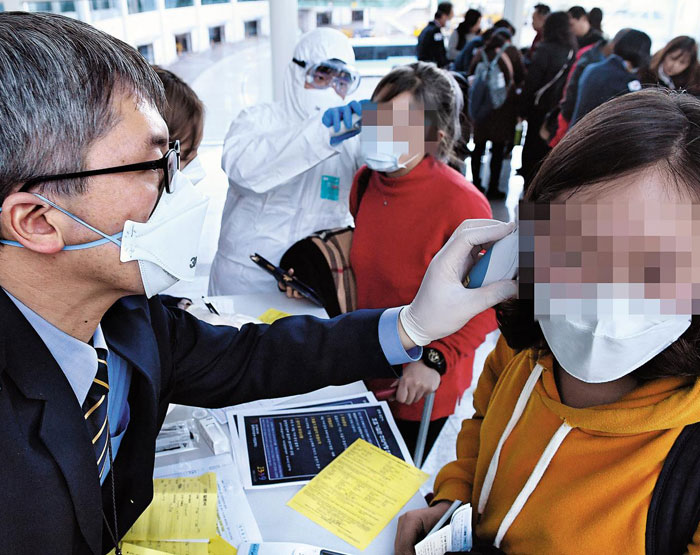 국내에서 '우한(武漢) 폐렴' 확진 환자가 처음으로 확인된 20일 오후 인천국제공항 제2 터미널에서 국립검역관리소 직원이 중국 우한에서 항공편으로 입국한 승객의 체온을 재고 있다.
