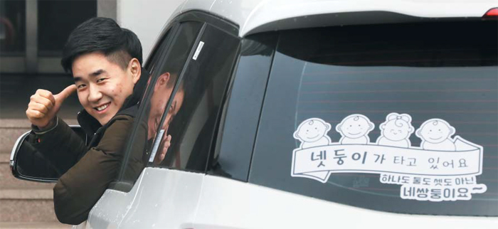 하나도 둘도 셋도 아닌 넷둥이가 타고 있어요 - 작년 12월 네 쌍둥이 아빠가 된 이한솔(31)씨는 7인승 승합차를 샀다. IT 회사 디자인팀장인 이씨가 네 쌍둥이를 그린 스티커를 직접 만들어 뒤 유리창에 붙였다. 지난 19일 경기도 부천 아파트 주차장의 승합차 운전석에서 이씨가 엄지를 들어올리고 있다.