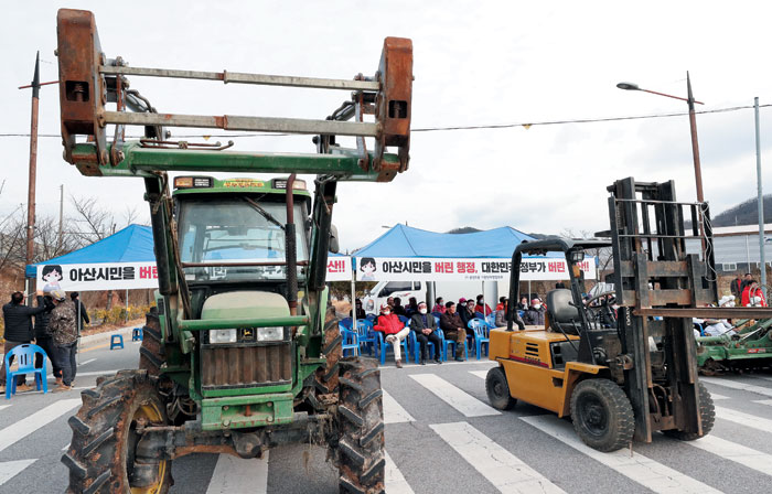 29일 오후 충남 아산시 초사동 경찰인재개발원 정문 앞에서 아산 지역 주민들이 왕복 4차선 도로를 농기계들로 가로막고 항의 시위를 하고 있다.