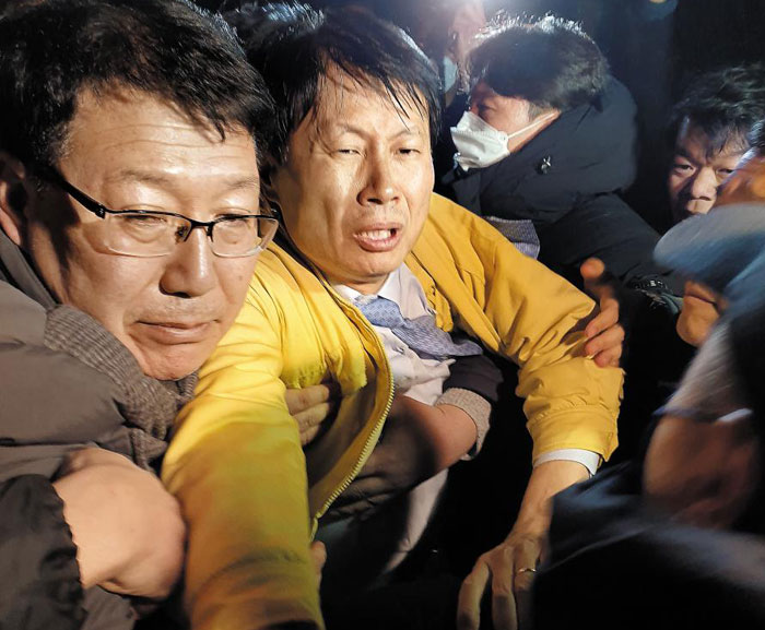 김강립(왼쪽 둘째) 보건복지부 차관이 29일 오후 10시 30분쯤 충북 진천 국가공무원 인재개발원 정문 앞에서 주민들의 거센 항의가 이어지자 경찰의 호위를 받으며 현장을 빠져나가고 있다.