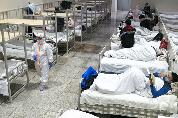 중국 후베이성 우한의 한 대형 전시장을 개조한 임시병원에서 보호복을 입은 의료진이 우한 폐렴 환자들 옆을 지나가고 있다. /AP 연합뉴스