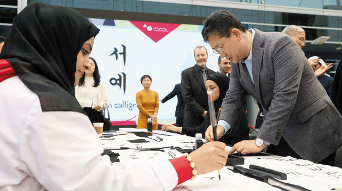 지난달 19일 아랍에미리트 두바이자이드대학에 마련된 세종학당을 찾은 박양우 문체부 장관이 히잡 쓴 학생들과 함께 붓글씨로 한글을 써보고 있다. 