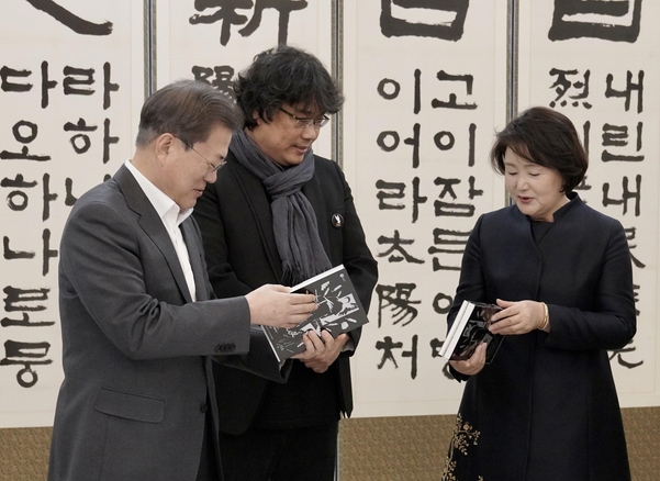 문재인 대통령과 김정숙 여사가 20일 청와대에서 영화 '기생충' 제작진, 배우 초청 오찬에 앞서 봉준호 감독의 선물을 받고 있다. 봉 감독은 각본집과 스토리북을 선물했다. /연합뉴스