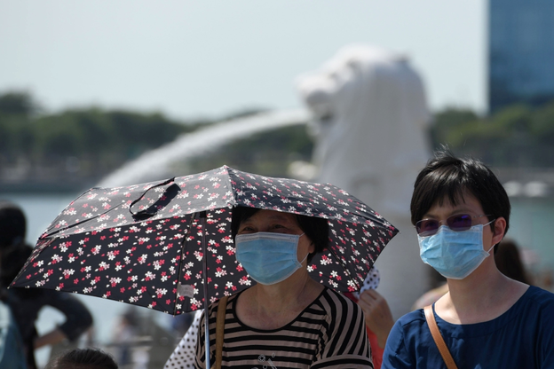 싱가포르의 상징인 ‘머라이언’ 분수 앞을 마스크를 쓴 여성들이 지나고 있다. /트위터 캡처