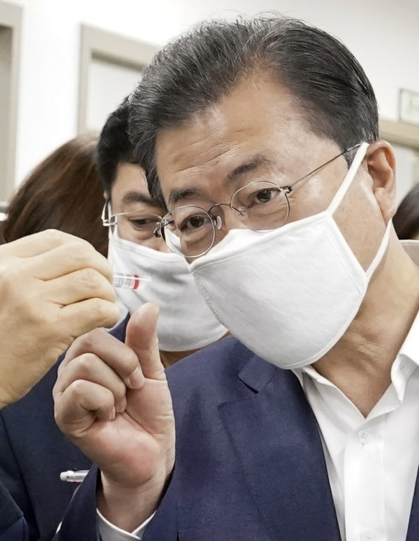 문재인 대통령이 25일 코로나19 진단시약 긴급사용 승인 기업 중 하나인 송파구 씨젠에서 시약 제품을 보고 있다. /연합뉴스
