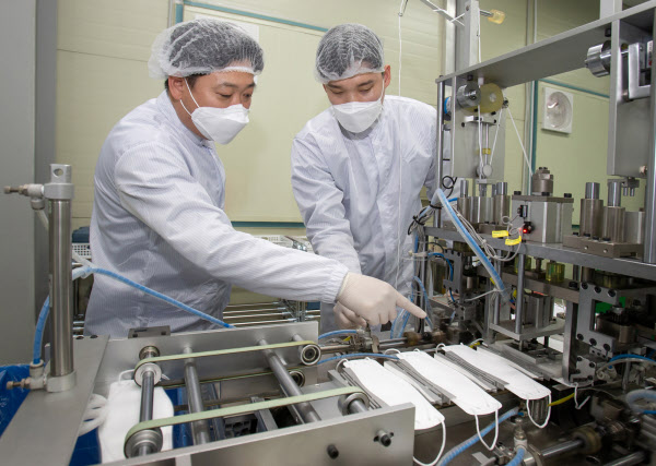 이달 16일 대전시 유성구에 있는 마스크 제조기업 '레스텍'에서 박나원 공장장(오른쪽)과 권오창 삼성전자 스마트공장지원센터 멘토가 마스크 본체와 귀 끈 연결 상태를 점검하고 있다./삼성전자 제공