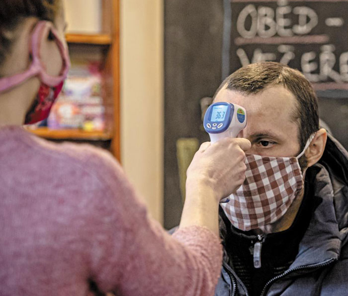 31일 체코 프라하에서 한 시민이 천으로 만든 마스크를 쓰고 체온을 재고 있다. 