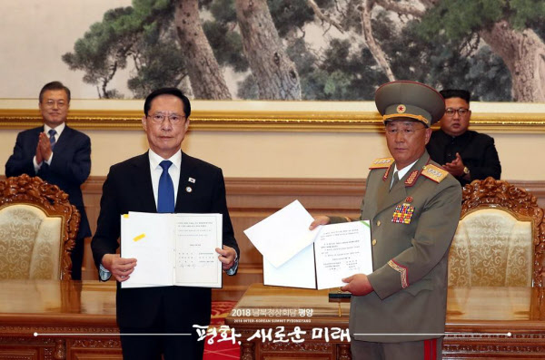 Defense Minister Song Young-moo (second left) and the North Korean People's Armed Forces Award (third left) are exchanging military agreements to implement the Panmunjom Declaration on September 19 last year at the pension from Pyeongyang department store. President Moon Jae-in and North Korean leader Kim Jong-un are applauding behind them. / Pyongyang Photo Joint Foundation