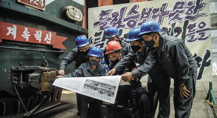 북한 평양에 있는 김종태전기기관차연합기업소 노동자들이 17일 개성 남북공동연락사무소 폭파 소식을 전하는 노동신문 기사를 읽고 있다.