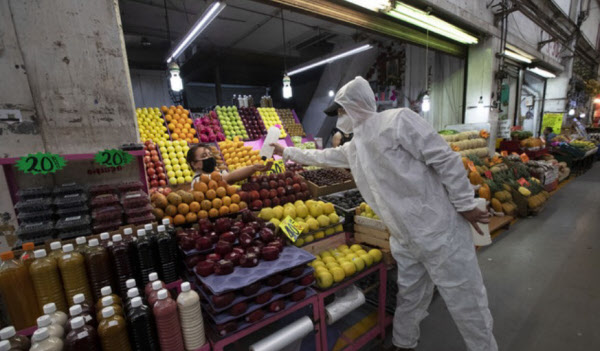 지난 18일 멕시코시티의 한 시장에서 보건요원이 코로나 바이러스 억제를 위해 시장 내 상인에게 손소독제를 건네고 있다. /AP 연합뉴스