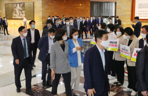 더불어민주당 의원들이 29일 오후 서울 여의도 국회 본회의장에 입장하고 있다. 로텐더홀에 정의당 의원들이 '등록금 반환 추경예산 편성' 손팻말을 들고 서 있다./연합뉴스