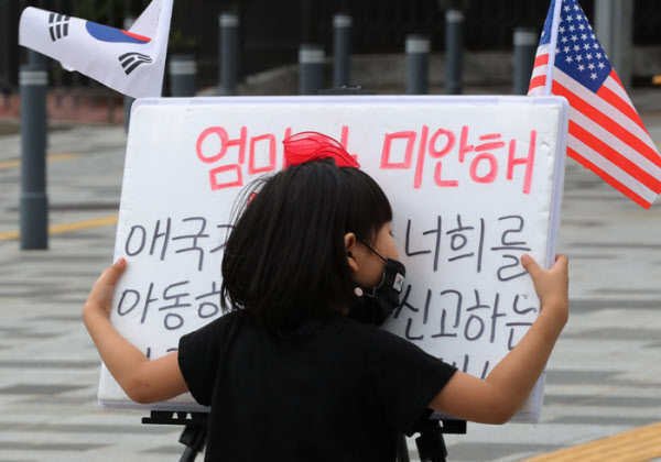 아직도 엄마의 손이 많이 필요한 6살짜리 딸 이정아양이 '엄마가 미안해..'라고 쓰여진 팻말을 보듬고 있다.아이들은 애국가 맘에게 존재 이유중의 하나이다. /이진한기자