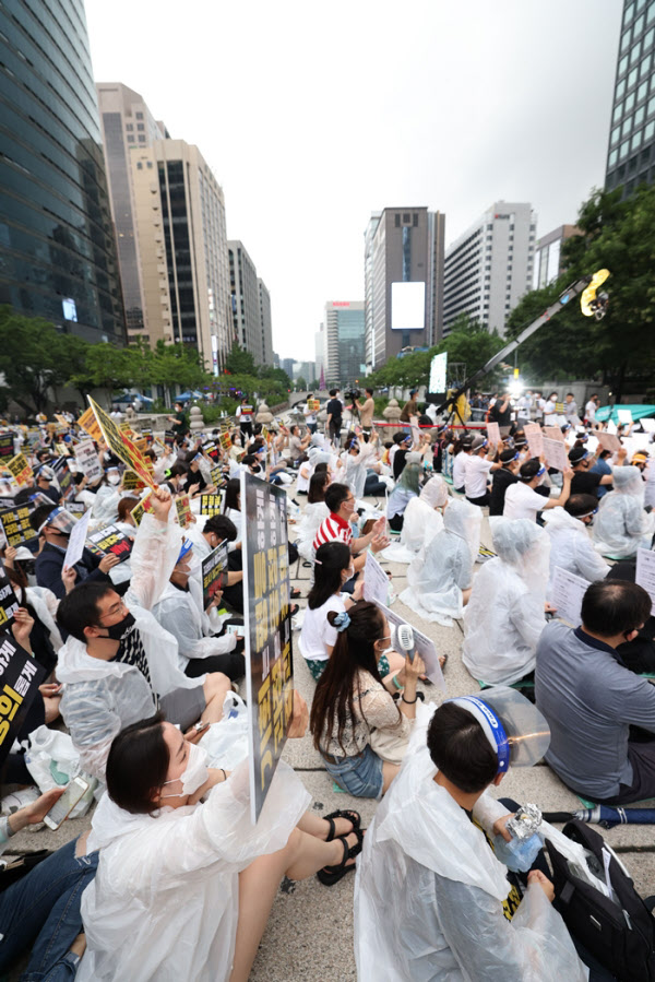 1일 서울 중구 청계천로 일대에서 열린 '투명하고 공정한 정규직 전환 촉구 문화제' 참가자들이 비옷과 마스크를 착용하고 자리에 앉아 손팻말을 들어 보이고 있다. /연합뉴스