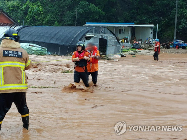 2일 집중호우가 내린 충북 단양의 한 마을 주민들이 불어난 빗물로 마을 진입로가 끊기자 119구조대의 도움을 받아 안전지대로 대피하고 있다. /연합뉴스