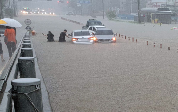 지난 3일 충남 천안시 한 도로에서 시민들이 물에 빠진 차에서 내려 탈출하고 있다. /연합뉴스