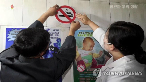 북한 금연연구보급소 직원들이 건물 벽면에 흡연 금지 스티커를 부착하고 있다. /조선중앙TVㆍ연합뉴스