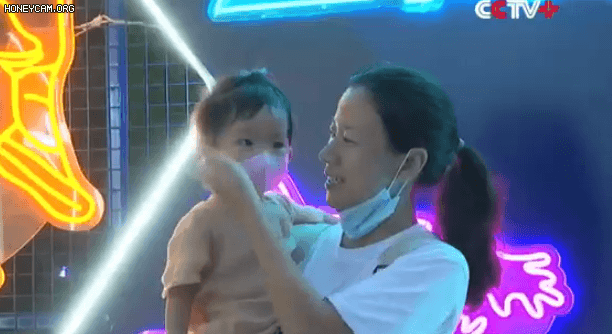 지난 18일 우한에서 열린 대규모 맥주축제에서 사진 촬영을 위해 엄마가 아기 마스크를 벗기고 있다. /CGTV 캡처