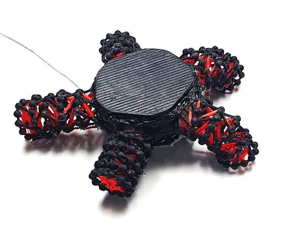 다리가 긴장된 구조로 만들어진 불가사리 로봇.  빨간색 구조는 검은 인대에 의해 당겨져 모양이 바뀝니다 ./Science Robotics