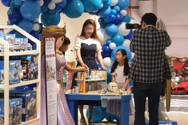 31일 오전 서울 소공동 신세계백화점 본점 7층 이벤트홀에서 백화점 직원이 어린이 모델들의 마스크를 벗게한 뒤 홍보 사진을 찍고 있다. /한경진 기자