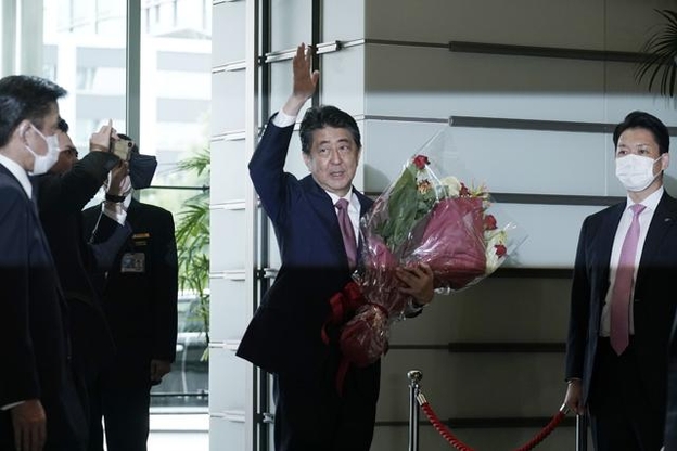 아베 신조 전 일본 총리가 16일 꽃다발을 안고 도쿄 총리관저를 떠나면서 손을 흔들고 있다. /연합뉴스